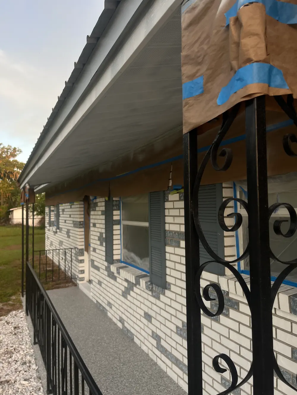 Front of house windows and brick covered with plastic and tape.