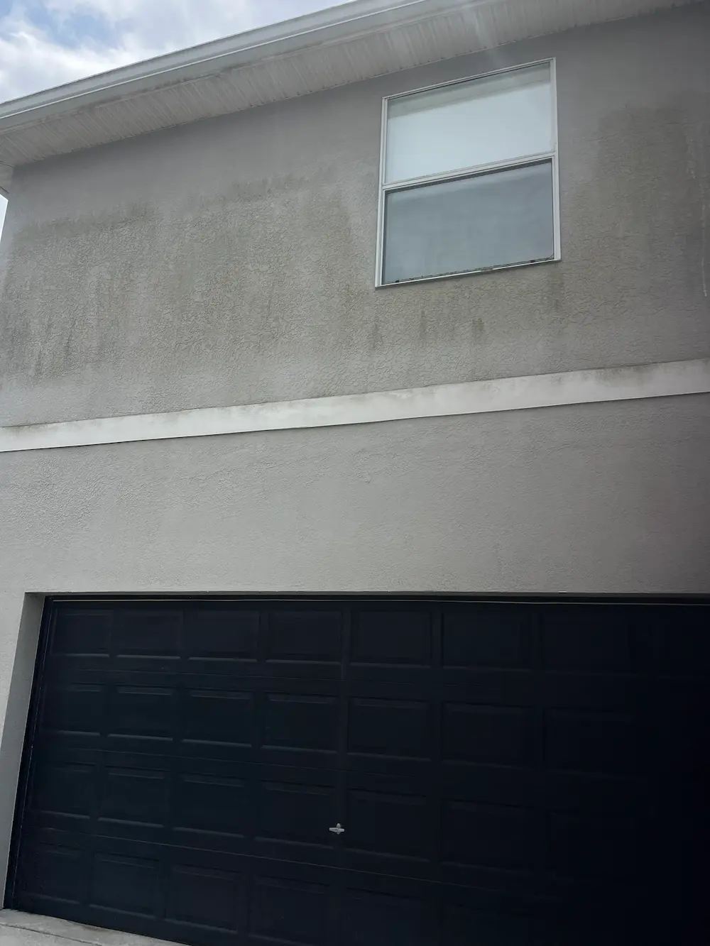 Algae on side of two story stucco home.