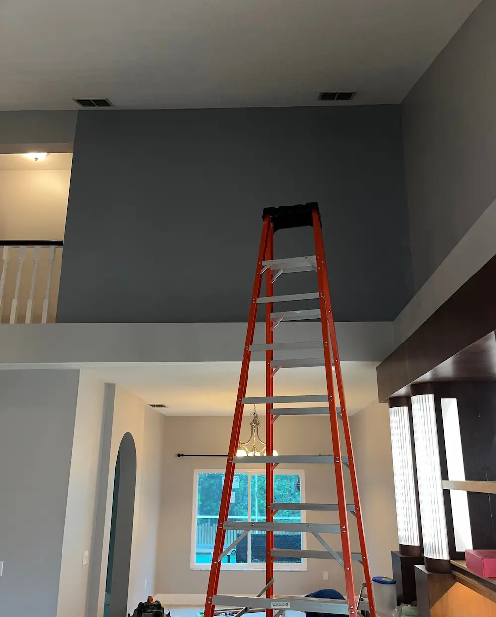 10 foot tall folding ladder inside a living room to paint a 16 foot tall wall.