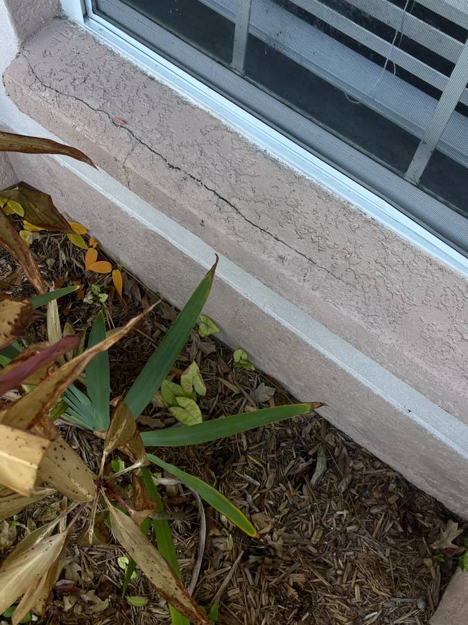 Stucco window sill with a large crack on the top.